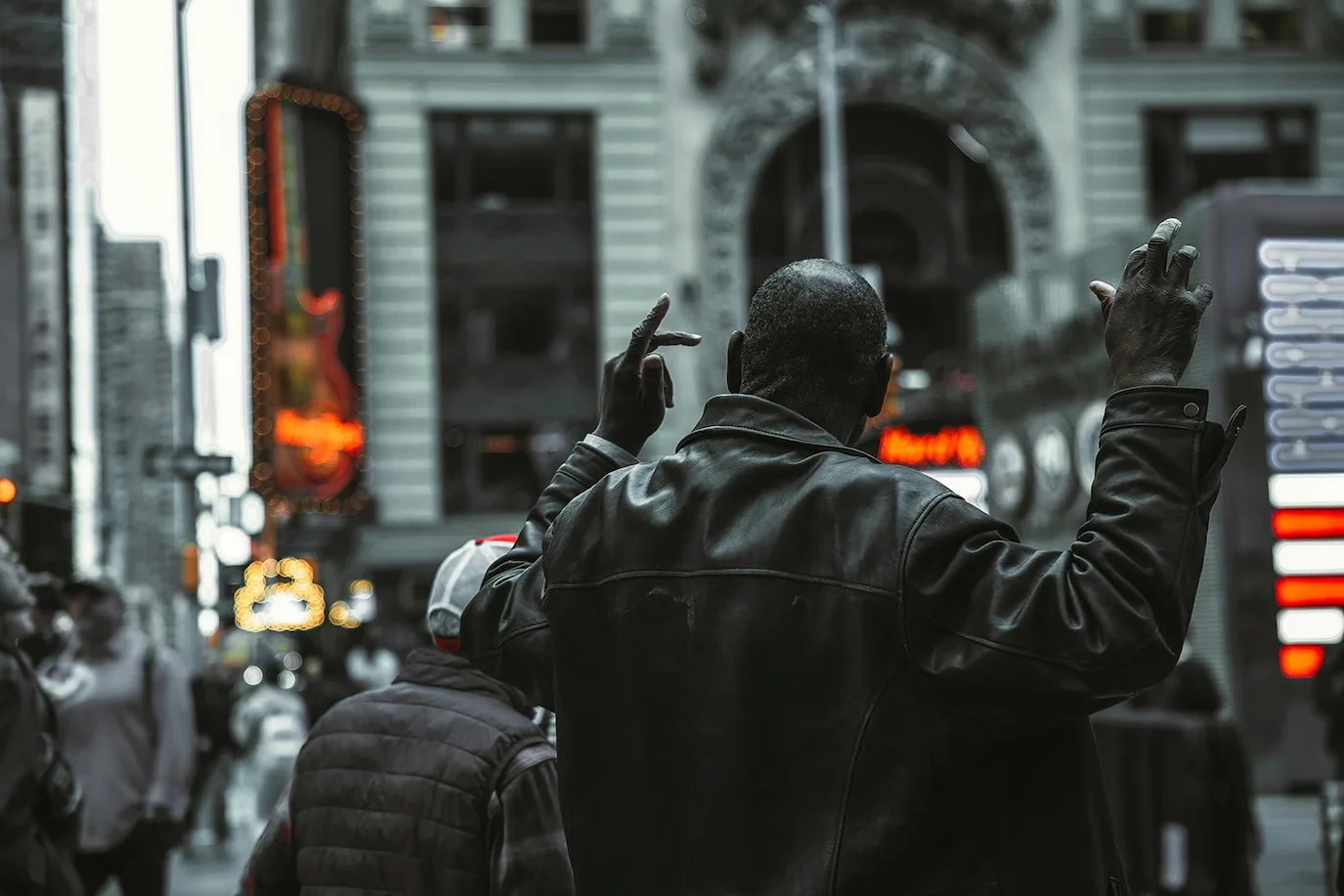 man raising hands in city street