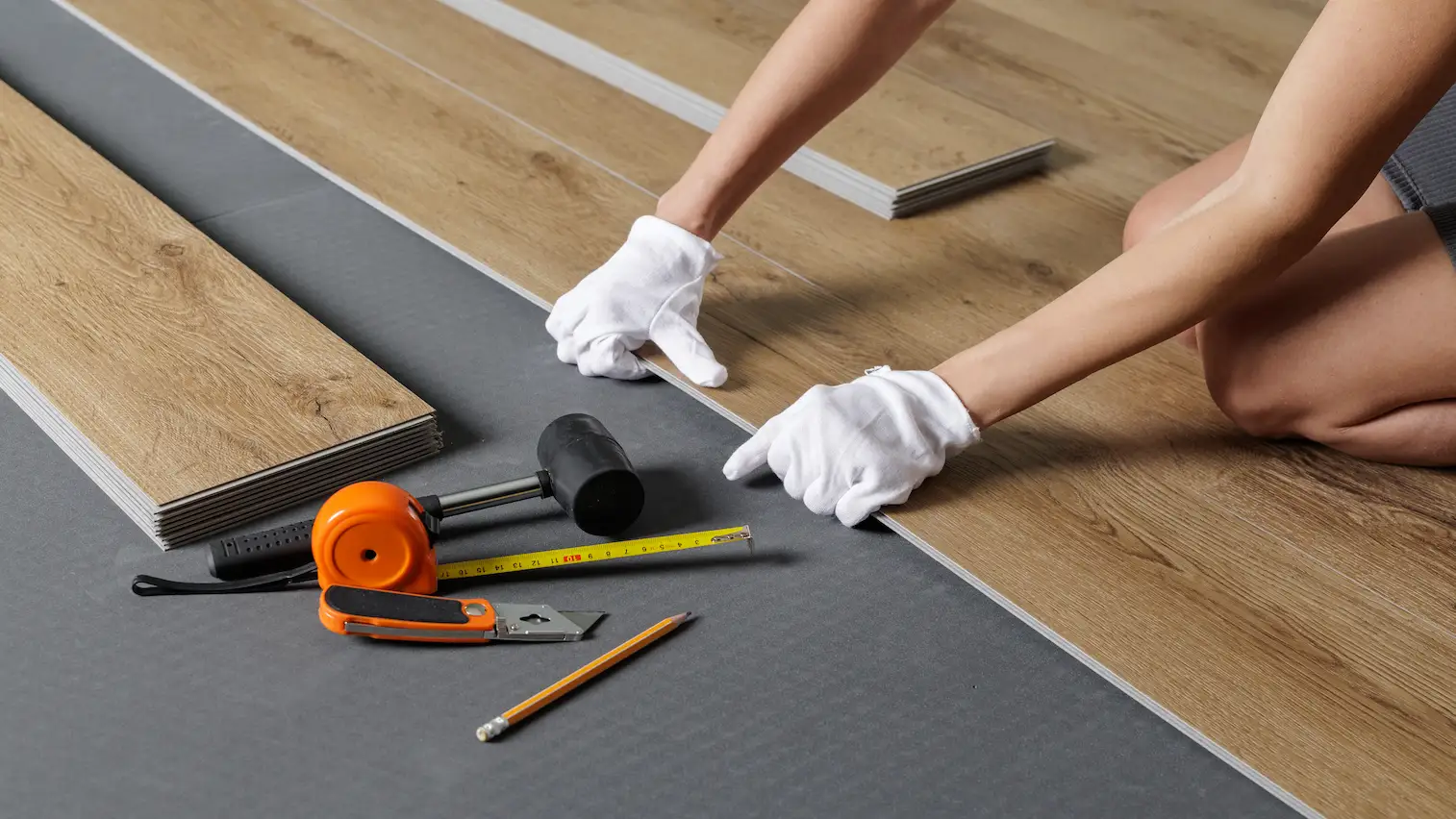 hands aligning spc vinyl plank on underlayment