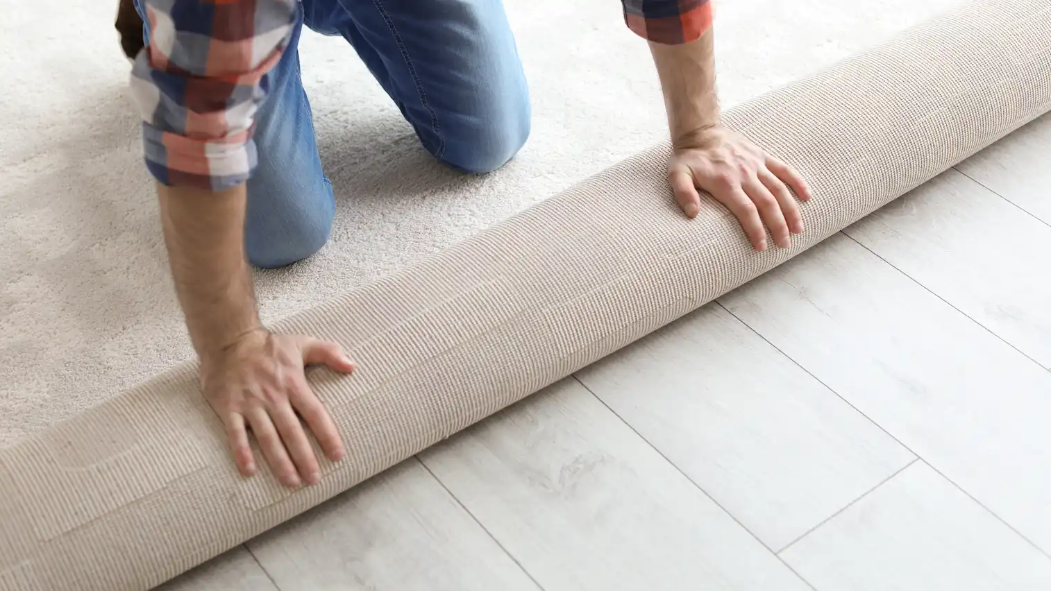 man rolling out new carpet flooring in room