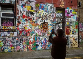 Person photographing graffiti wall