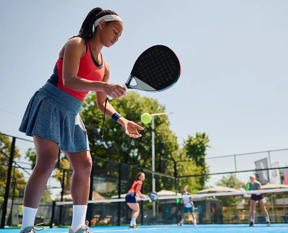 black woman serving the ball while playing paddle