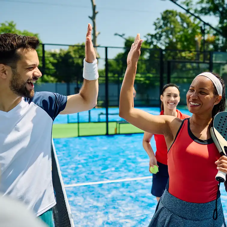 happy paddle tennis players giving high five to each other
