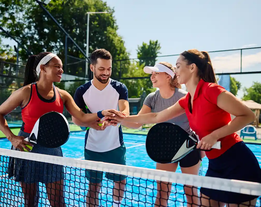 happy paddle tennis players joining hands in unity