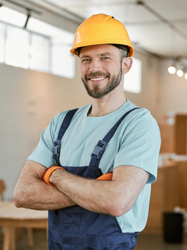 Cheerful male worker in helmet standing in workshop