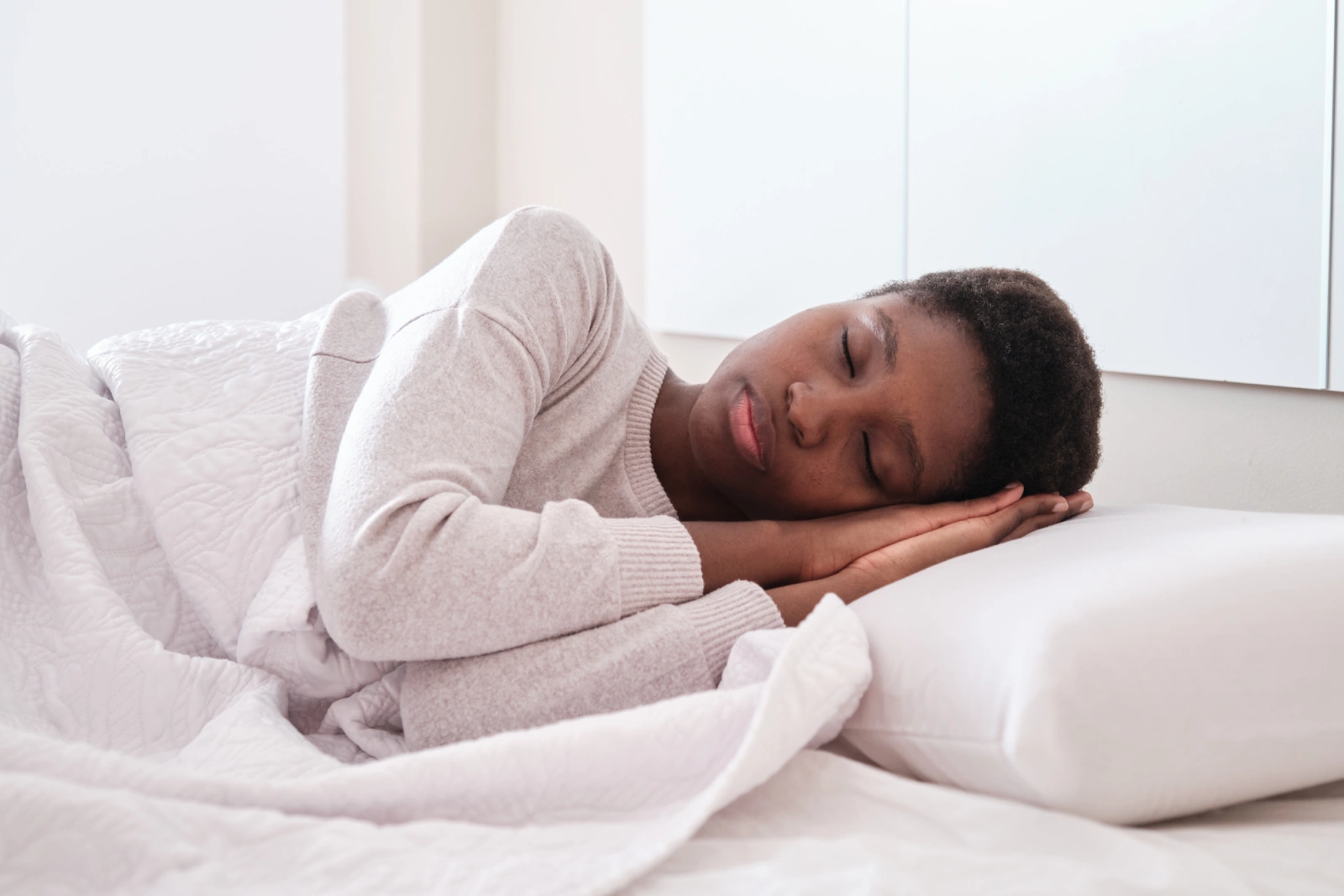 black female sleeping in bed with hands under head