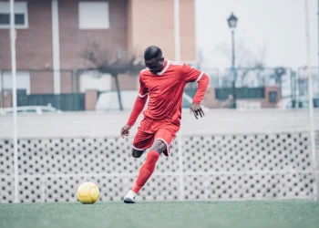 african soccer player with red outfit playing soccer