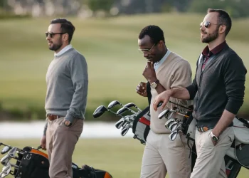 multiethnic golfers holding bags with golf clubs