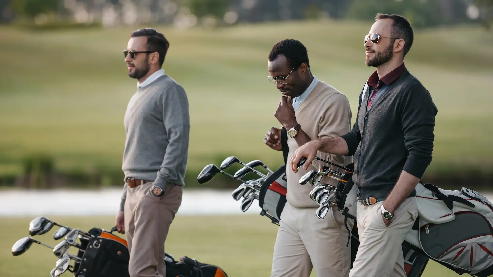 multiethnic golfers holding bags with golf clubs