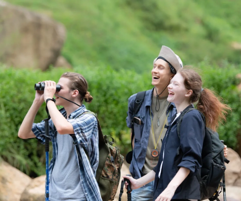 Group of tourists with backpacks walking on the trail in the river and mountains