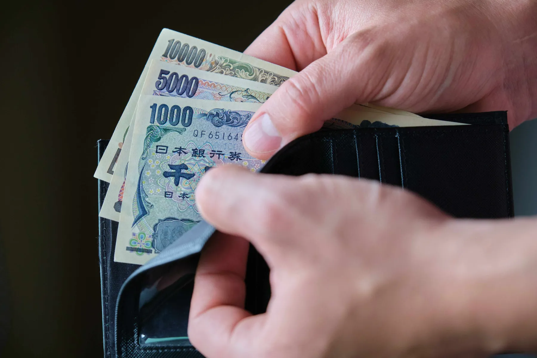 hand holding a wallet with japanese yen banknotes
