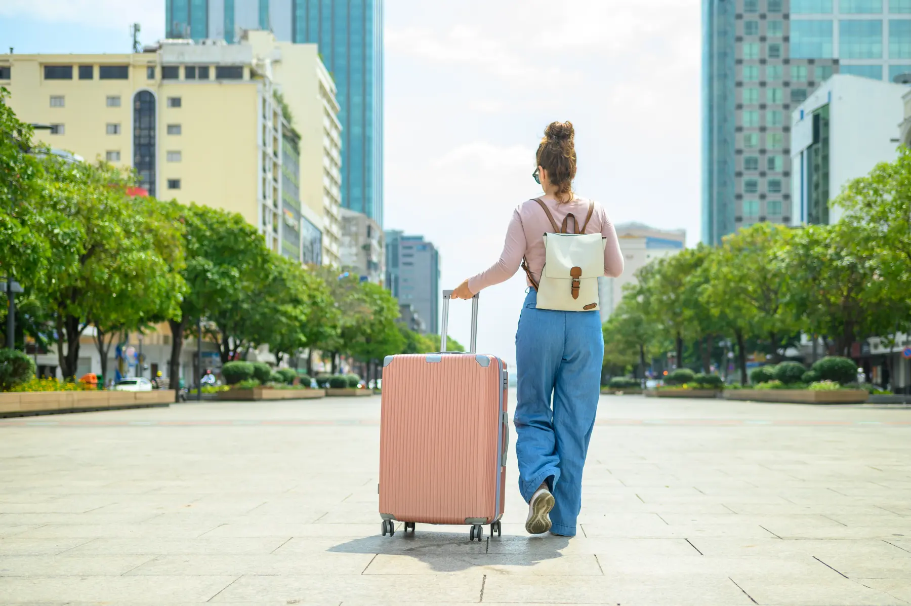 unrecognizable woman with suitcase and backpack
